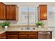 A kitchen sink features wood cabinets, granite countertops, and stainless steel appliances at 43884 W Kramer Ln, Maricopa, AZ 85138
