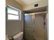 Bathroom features shower with metal frame, window for lighting, toilet and gray walls at 5342 E Des Moines St, Mesa, AZ 85205