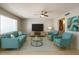 Bright living room with stylish teal furniture, ceiling fan, and large window at 5342 E Des Moines St, Mesa, AZ 85205