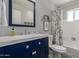 Charming bathroom featuring a navy vanity, framed mirror, and tub with shower at 701 N 55Th Pl, Mesa, AZ 85205