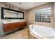 A bathroom featuring a soaking tub, double sink vanity, and unique glass block window at 8408 E Rancho Vista Dr, Scottsdale, AZ 85251