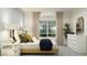 A cozy bedroom with a large window, a dresser and a decorative plant at 9550 W Catalina Dr, Phoenix, AZ 85037