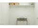 Bright laundry room with open shelf storage, laundry hamper and stacked towels at 9550 W Catalina Dr, Phoenix, AZ 85037