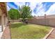 Spacious backyard featuring a lush lawn, mature trees, barbecue grill, and a privacy wall at 1114 N Leland Ct, Gilbert, AZ 85233