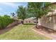 Well-kept backyard with mature trees, a covered patio, green lawn, and privacy fence at 1114 N Leland Ct, Gilbert, AZ 85233