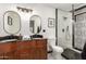 Stylish bathroom with double sinks, wooden cabinets, tiled floors, and a walk-in shower at 12866 W Orange Dr, Litchfield Park, AZ 85340