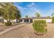 View of the home's exterior with gravel landscaping, mature trees, and a paved walkway leading to the front entrance at 12866 W Orange Dr, Litchfield Park, AZ 85340