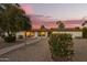 Charming single-story home featuring a lush, landscaped yard and inviting walkway under a beautiful sunset sky at 12866 W Orange Dr, Litchfield Park, AZ 85340