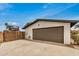 A single car garage with a white brick facade, brown door, and adjacent parking area at 12866 W Orange Dr, Litchfield Park, AZ 85340