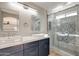 Modern bathroom with double sinks, stylish vanity, and a decorative tiled shower with glass doors at 13170 W Clarendon Ave, Litchfield Park, AZ 85340