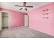 Pink bedroom featuring carpeted floor, a ceiling fan and shelving unit at 15551 W Poinsettia Dr, Surprise, AZ 85379