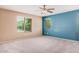 Bright bedroom with two windows, plush carpet, a ceiling fan and painted accent wall at 15551 W Poinsettia Dr, Surprise, AZ 85379