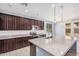 Bright kitchen featuring dark cabinets, stainless steel appliances, tile backsplash, and a large island with a sink at 15551 W Poinsettia Dr, Surprise, AZ 85379