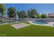Backyard featuring a private pool surrounded by lush greenery and a well-maintained artificial turf area at 1610 W Maplewood St, Chandler, AZ 85286