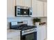 Close-up of modern stainless steel microwave and gas range with white cabinetry at 16714 W Audrey Ln, Surprise, AZ 85387