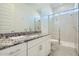 Bathroom showcasing a granite countertop, white cabinets, and walk-in shower with glass door at 16933 W Bronco Trl, Surprise, AZ 85387