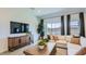 A bright living room features a sectional couch, coffee table, TV, and backyard access at 16933 W Bronco Trl, Surprise, AZ 85387