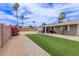Backyard with a long artificial lawn, brick pavers, mature trees, and a covered patio at 2821 E Larkspur Dr, Phoenix, AZ 85032