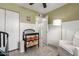 Bedroom with green walls, wainscotting, a ceiling fan, a comfortable chair, and changing table with storage at 2821 E Larkspur Dr, Phoenix, AZ 85032