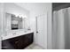 Well-lit bathroom featuring a double vanity, large mirror, and a shower with a curtain at 31051 W Amelia Ave, Buckeye, AZ 85396