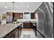 Well-equipped kitchen featuring dark wood cabinets, granite countertops, stainless steel appliances, and island with barstool seating at 32347 N Vernal Ln, San Tan Valley, AZ 85144