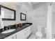 Bright bathroom featuring dual sinks, black countertops, sleek fixtures, and modern lighting at 3402 E Sells Dr, Phoenix, AZ 85018