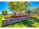 A well-maintained community sign with flowers, lush lawn, and mature trees, creating a welcoming entrance at 4038 E Wrangler Ct, Gilbert, AZ 85297