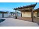A beautifully designed outdoor patio with a pergola, stone fire pit, and lush greenery for relaxation at 4202 W Purdue Ave, Phoenix, AZ 85051