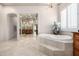 Bright bathroom featuring tile floors, a chandelier, soaking tub, and doorways with arched details at 4328 N Pinnacle Ridge Cir, Mesa, AZ 85207