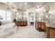 Spacious primary bathroom with dual vanities, stone tile, soaking tub, arched doorways, and chandelier at 4328 N Pinnacle Ridge Cir, Mesa, AZ 85207