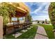 Covered outdoor bar area with seating, stone accents, manicured lawn, pool and mountain views in this luxury backyard at 4328 N Pinnacle Ridge Cir, Mesa, AZ 85207