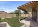 Inviting covered patio overlooks the artificial lawn, complemented by block fencing ensuring backyard privacy at 4404 W Ellis St, Laveen, AZ 85339
