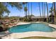 A large pool with rock feature and surrounded by lush greenery and towering palms at 4801 E Horseshoe Rd, Paradise Valley, AZ 85253