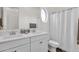 Clean bathroom featuring double sinks, a round window, and a shower/tub with a white curtain at 6565 E Thomas Rd # 1096, Scottsdale, AZ 85251
