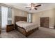 Charming bedroom with wooden bed frame, ceiling fan, and windows with patterned curtains at 887 W Santa Gertrudis Trl, San Tan Valley, AZ 85143