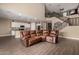 Spacious living room features a comfortable brown leather couch, open floor plan, and staircase at 887 W Santa Gertrudis Trl, San Tan Valley, AZ 85143