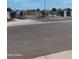 Entrance to the community featuring decorative gates, lush landscaping, and a paved road at 9137 W Sells Dr, Phoenix, AZ 85037