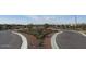 Landscaped entrance to the neighborhood with decorative plants and manicured flowerbeds along a winding road at 9137 W Sells Dr, Phoenix, AZ 85037