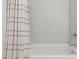 Close-up of a bathtub with tiled marble wall, shower curtain, and modern faucet at 10618 W Bloch Rd, Tolleson, AZ 85353