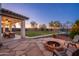 Outdoor living with a fire pit, seating, and covered patio in a landscaped backyard with a trampoline at 12110 W Rowel Rd, Peoria, AZ 85383