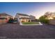 Large, landscaped backyard with a covered patio, lawn, gravel, and a view of the home's exterior at 12110 W Rowel Rd, Peoria, AZ 85383