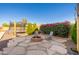 Inviting backyard with stone patio, fire pit, and lush landscaping creating a serene outdoor living space at 12110 W Rowel Rd, Peoria, AZ 85383