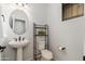 Charming powder room featuring a pedestal sink, and convenient shelving and toilet paper holder at 12110 W Rowel Rd, Peoria, AZ 85383