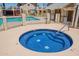 Community hot tub featuring blue mosaic tile design and metal safety rails, with pool in background at 2455 E Broadway Rd # 115, Mesa, AZ 85204