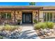 A front entry featuring a stone facade, a modern black double-door entrance, and desert landscaping at 28 E Winged Foot Rd, Phoenix, AZ 85022