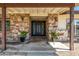Front porch with decorative stone columns, modern black door, and desert landscaping, creating a welcoming entrance at 28 E Winged Foot Rd, Phoenix, AZ 85022
