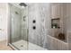 Modern walk-in shower featuring sleek tilework, dark fixtures, and built-in shelving at 28 E Winged Foot Rd, Phoenix, AZ 85022