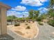 Landscaped backyard with gravel accents, trees, and various shrubbery under a blue sky at 31670 N Desert Willow Rd, San Tan Valley, AZ 85143
