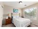 Comfortable bedroom with a brass headboard bed, nightstand, and a large window offering outdoor views at 41847 W Sparks Ct, Maricopa, AZ 85138