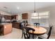 Cozy breakfast nook with a wood table and black chairs next to a kitchen with wood cabinets at 41847 W Sparks Ct, Maricopa, AZ 85138